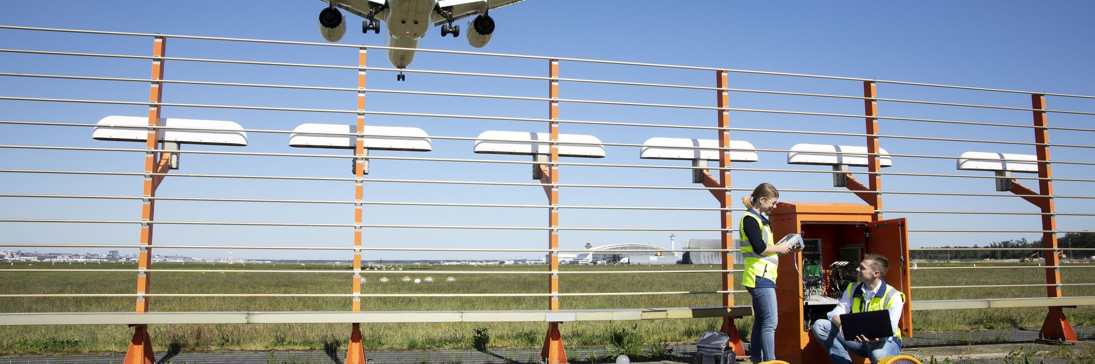 Zwei Flugsicherungsingenieure vor einem geöffneten Schaltkasten des Instrumentenlandesystems an einer Startbahn des Flughafens Frankfurt/M.