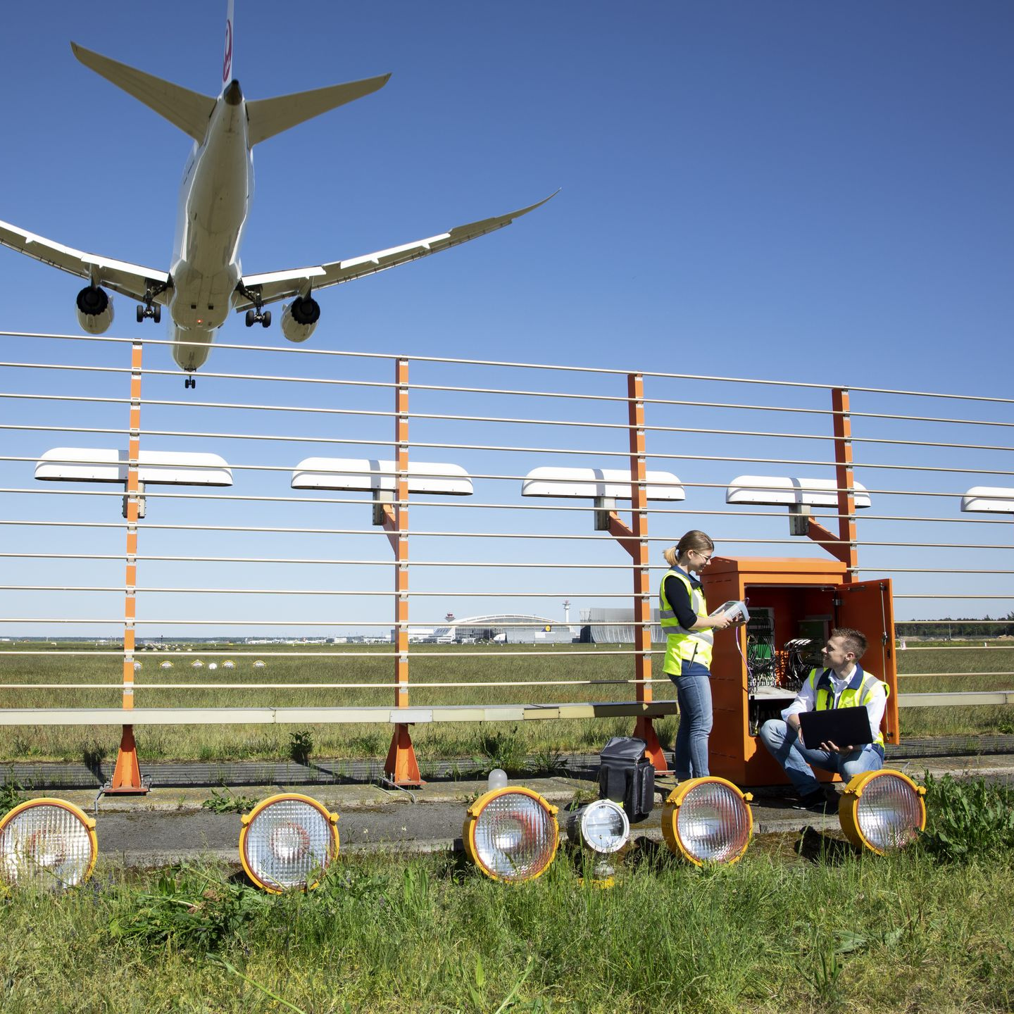 Zwei Flugsicherungsingenieure vor einem geöffneten Schaltkasten des Instrumentenlandesystems an einer Startbahn des Flughafens Frankfurt/M.