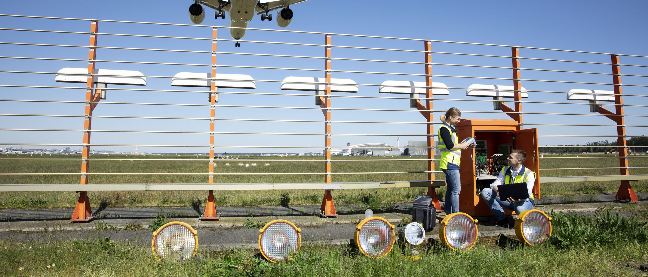 Zwei Flugsicherungsingenieure vor einem geöffneten Schaltkasten des Instrumentenlandesystems an einer Startbahn des Flughafens Frankfurt/M.